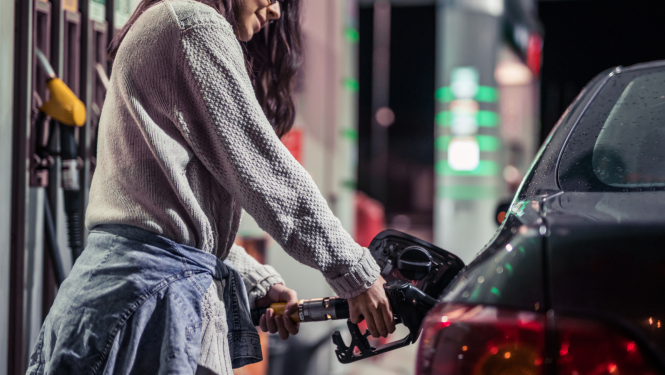 Sieviete degvielas uzpildes stacijā pilda degvielu auto