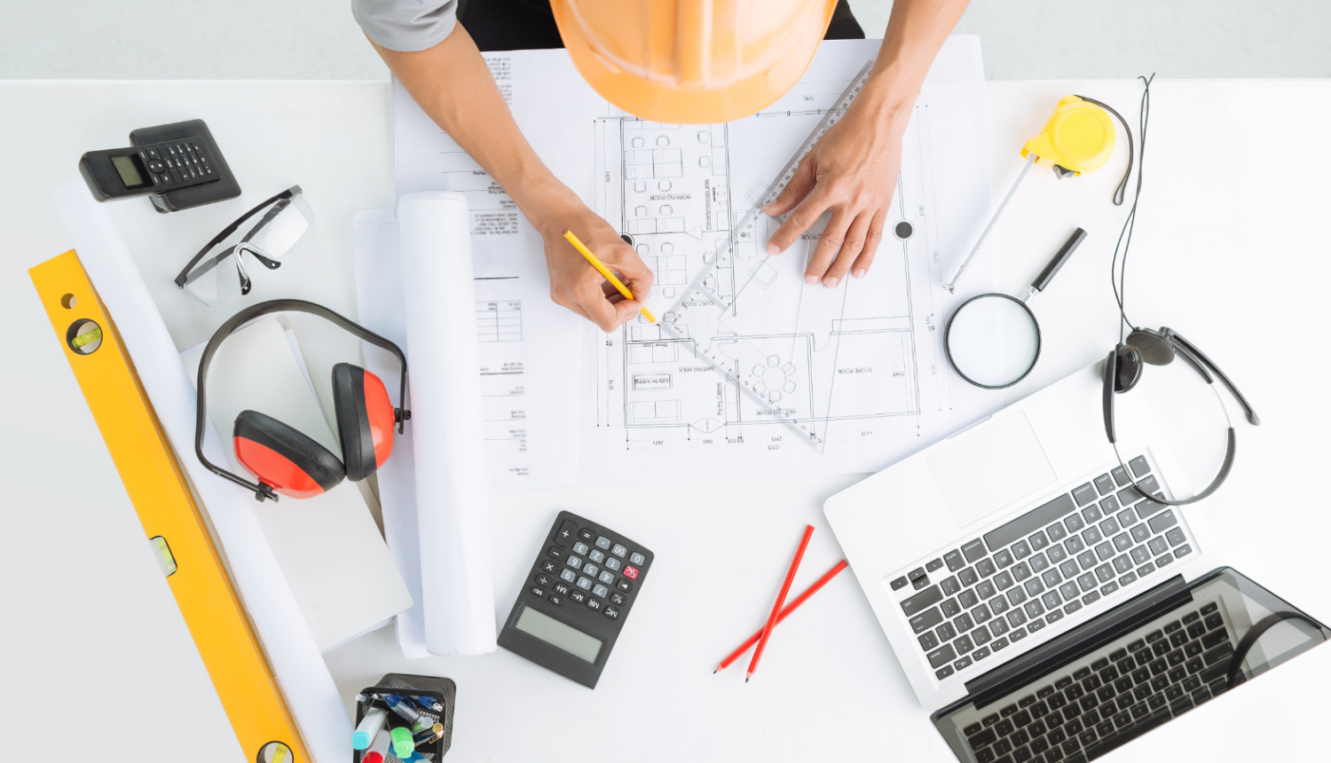 Būvspeciālists pie galda veic mērījumus un pierakstus